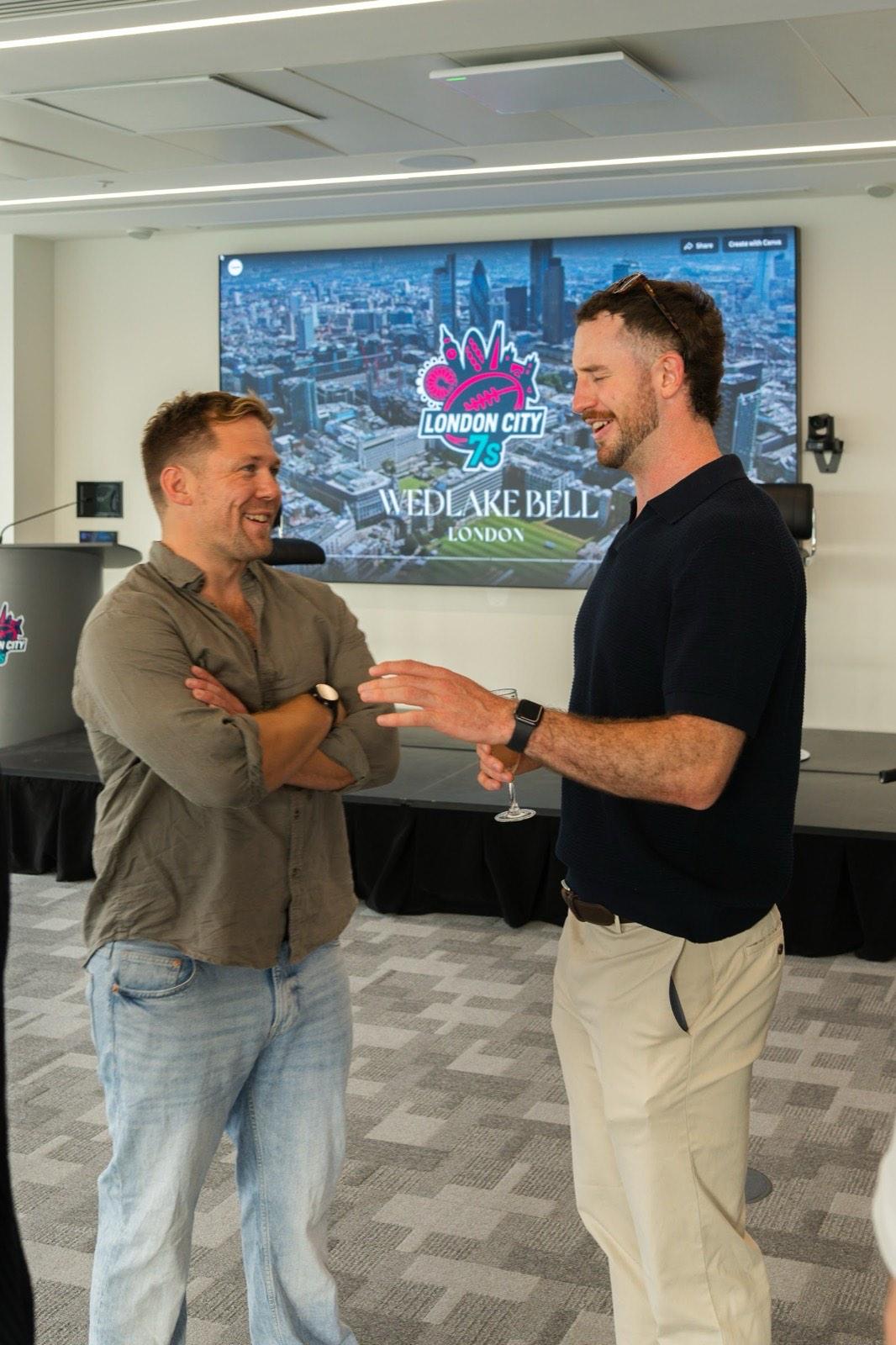 Guests networking in front of the London City 7s and Wedlake Bell screen